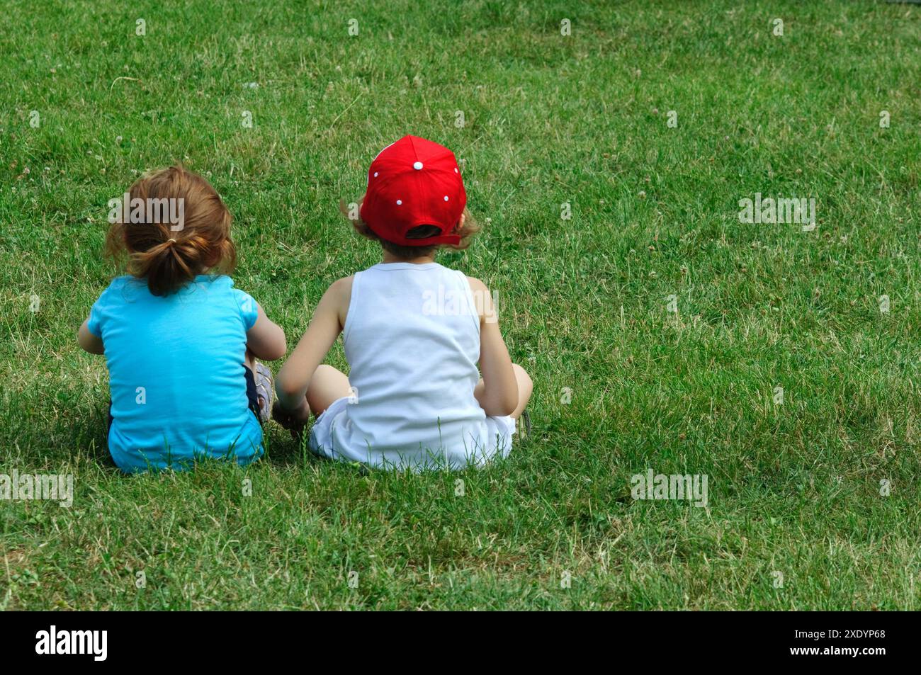 Two Young Girls on Sitting Grass, Rear View Stock Photo - Alamy