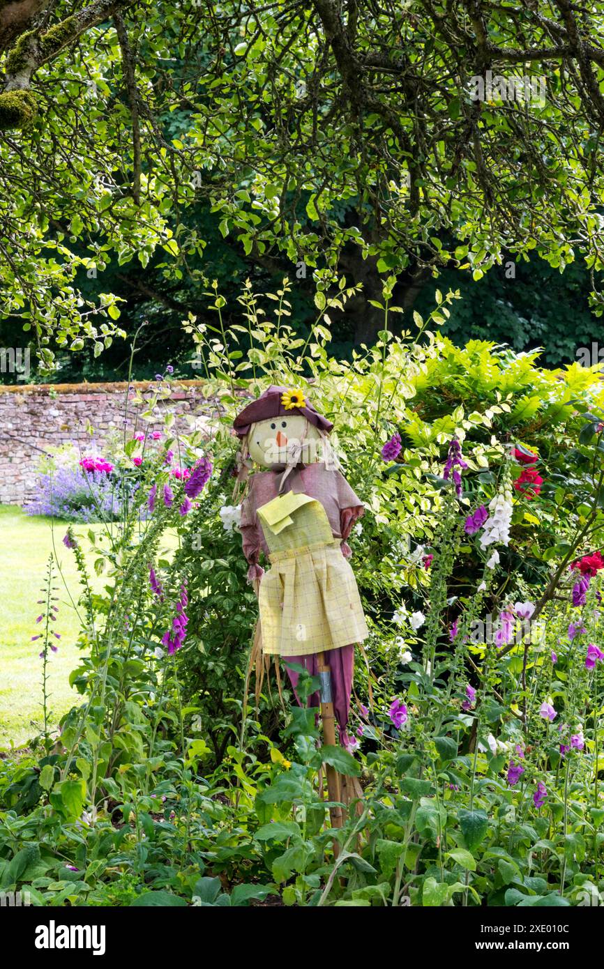 A scarecrow in a garden flower bed. Stock Photo
