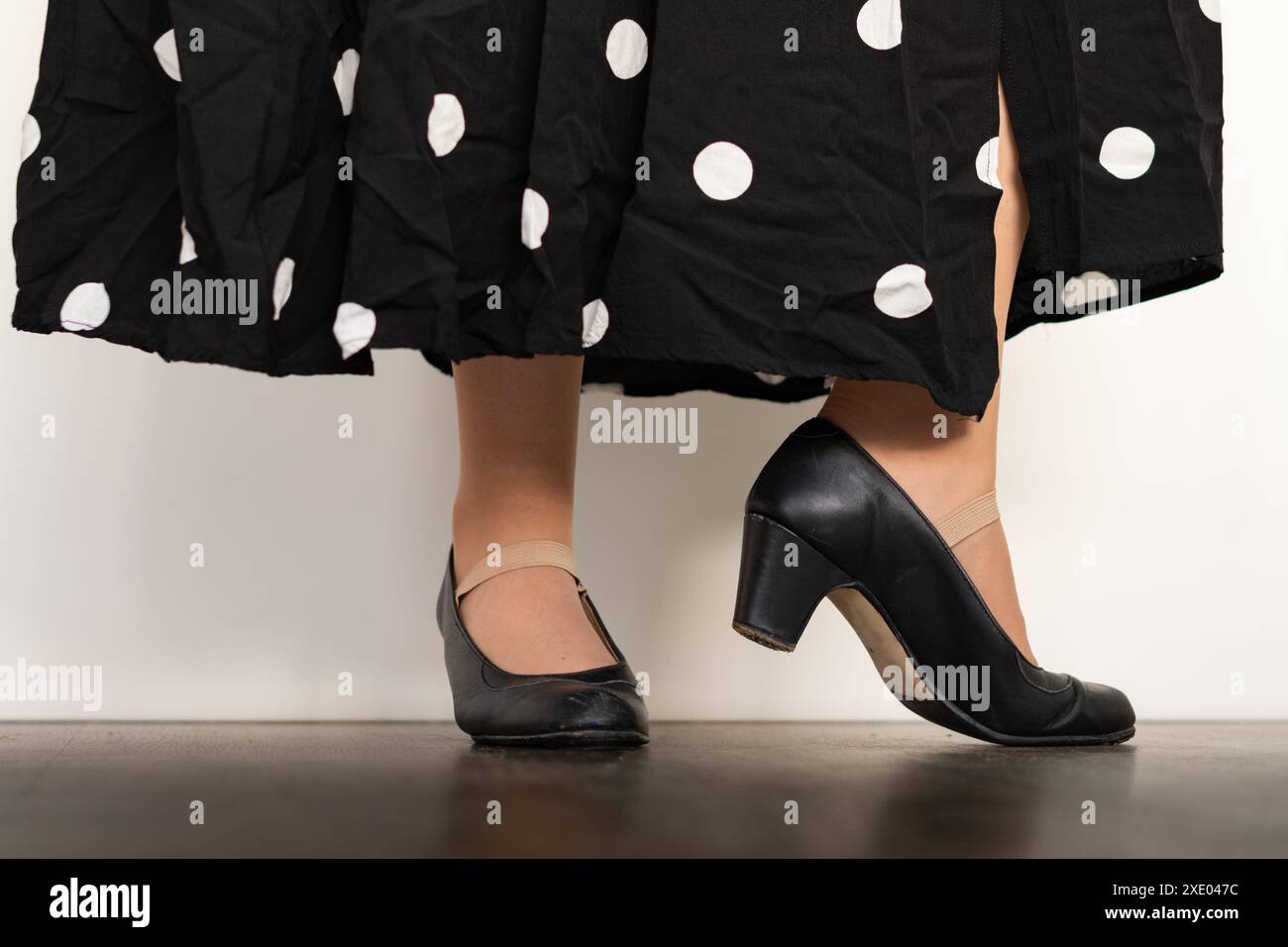 Legs of woman dancing flamenco with black clothes on wooden floor and white background Stock Photo