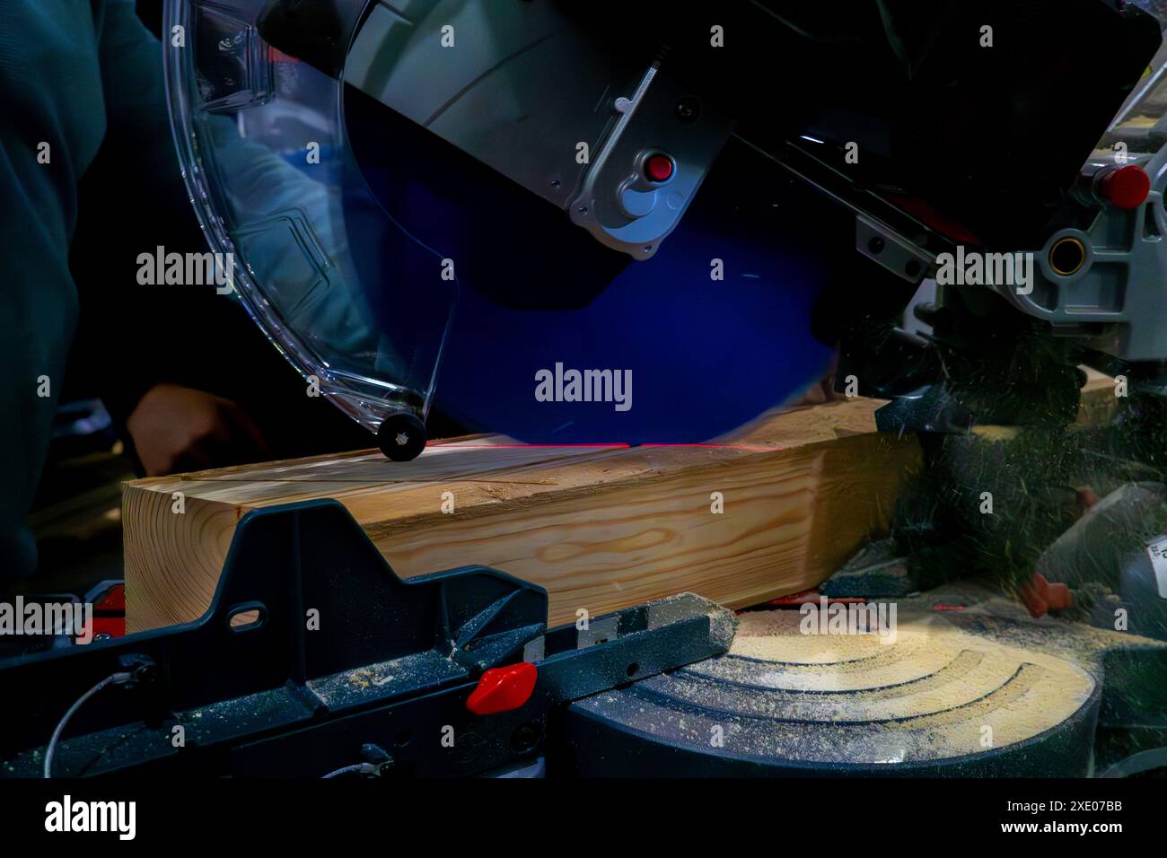 A worker cuts a wooden block using a circular saw Stock Photo
