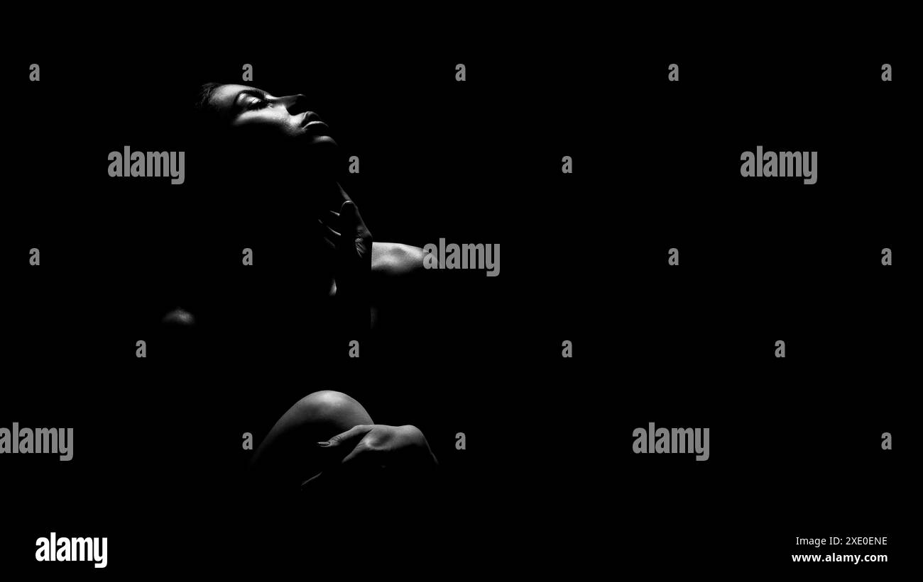 Silhouette of a Woman Looking Upward in a Dark Room Stock Photo