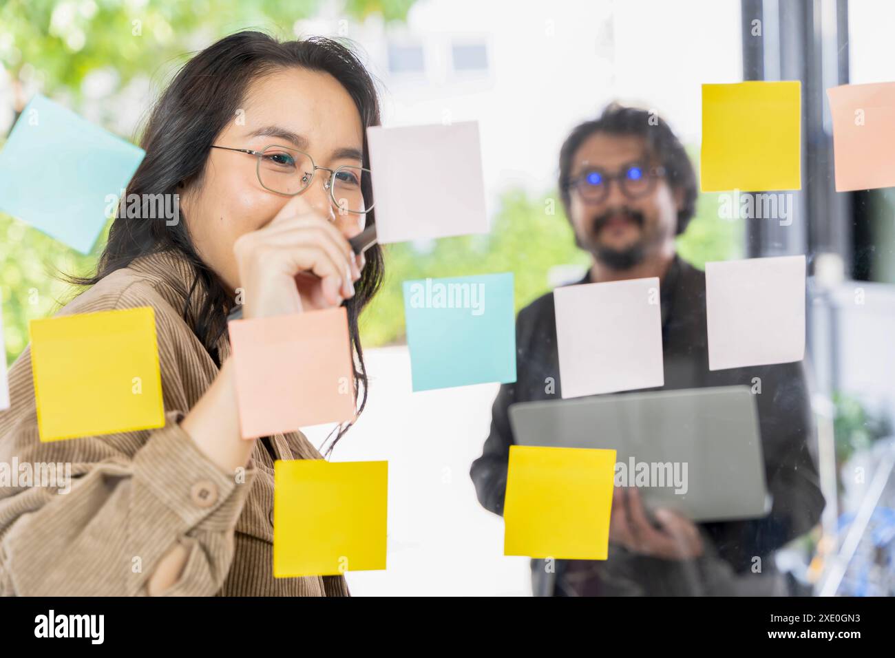 Business team meeting planning new strategy using colored sticky notes on mirror board in workplace, business teamwork brainstorm concept. Stock Photo