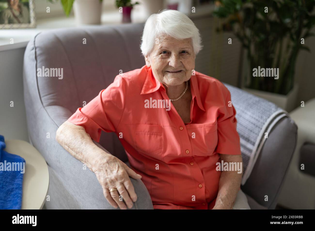 Portrait of happy senior woman sitting in armchair and looking at camera Stock Photo
