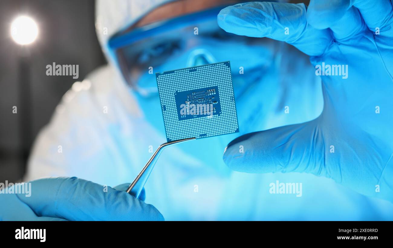 Scientist developer in protective suit holds microcircuit Stock Photo
