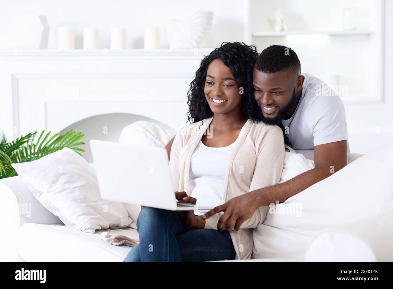 Couple Using Laptop on White Couch Stock Photo