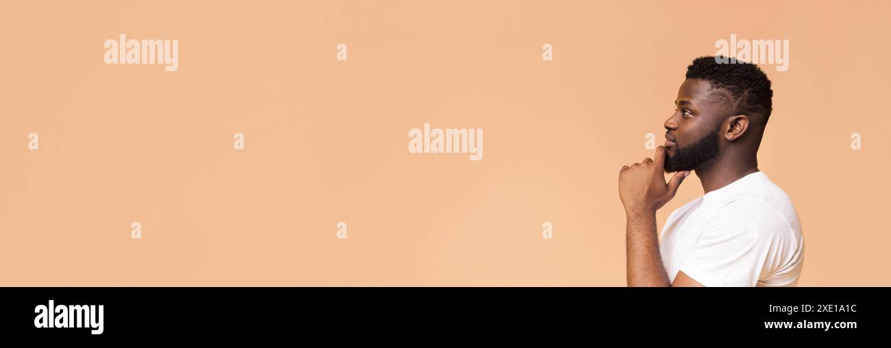 Man Thinking in Profile Against a Peach Background Stock Photo