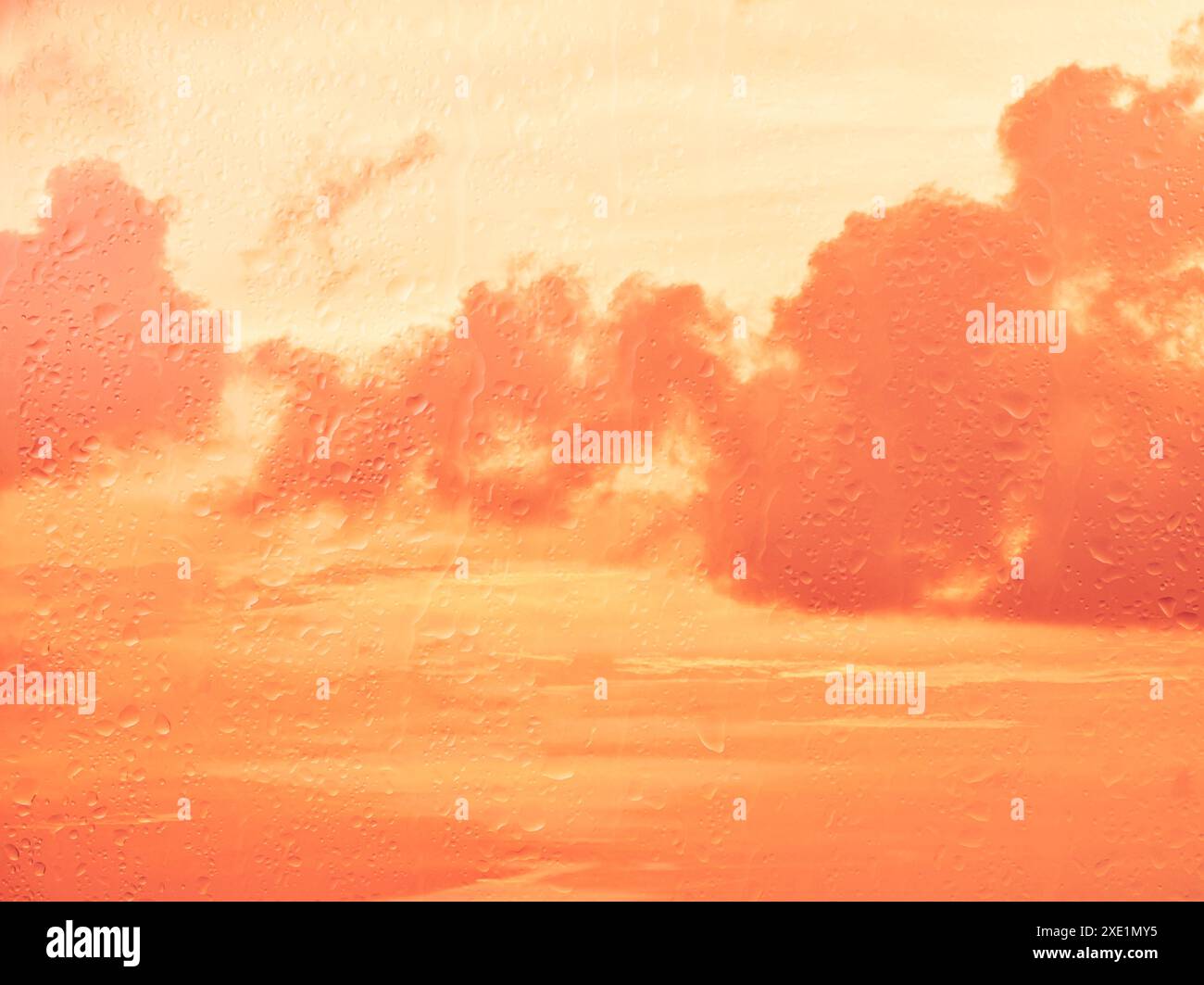 Raindrops on glass window over sunset sky Stock Photo