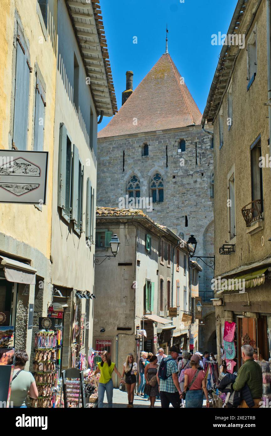 Carcassonne Aude France 06.24.24 Narrow medieval city street lined with shuttered historic timber framed buildings. Stone castle tower, arched windows Stock Photo