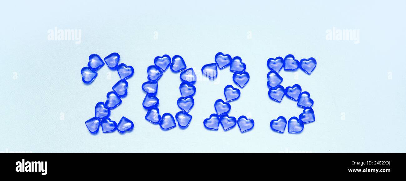 New Year 2025 inscription from glass hearts on a blue background