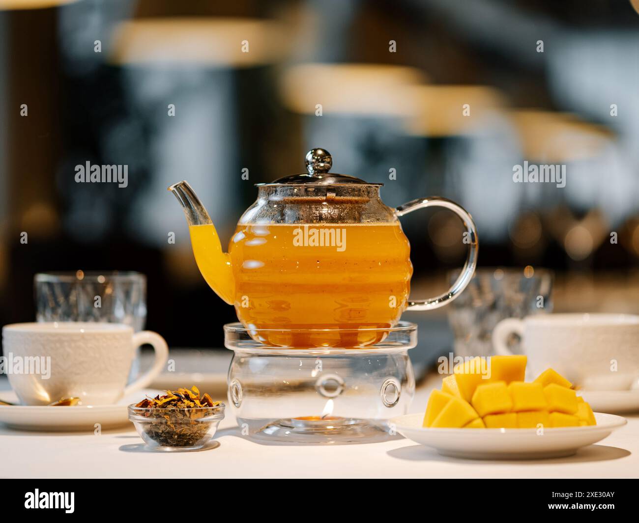 Mango herbal tea in teapot with warmer Stock Photo