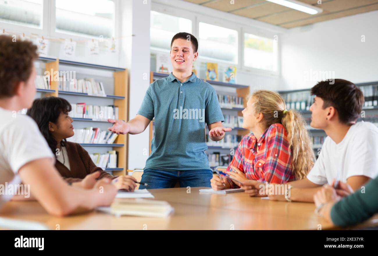 Schoolboy talking about his favorite book. Positive teenage students ...