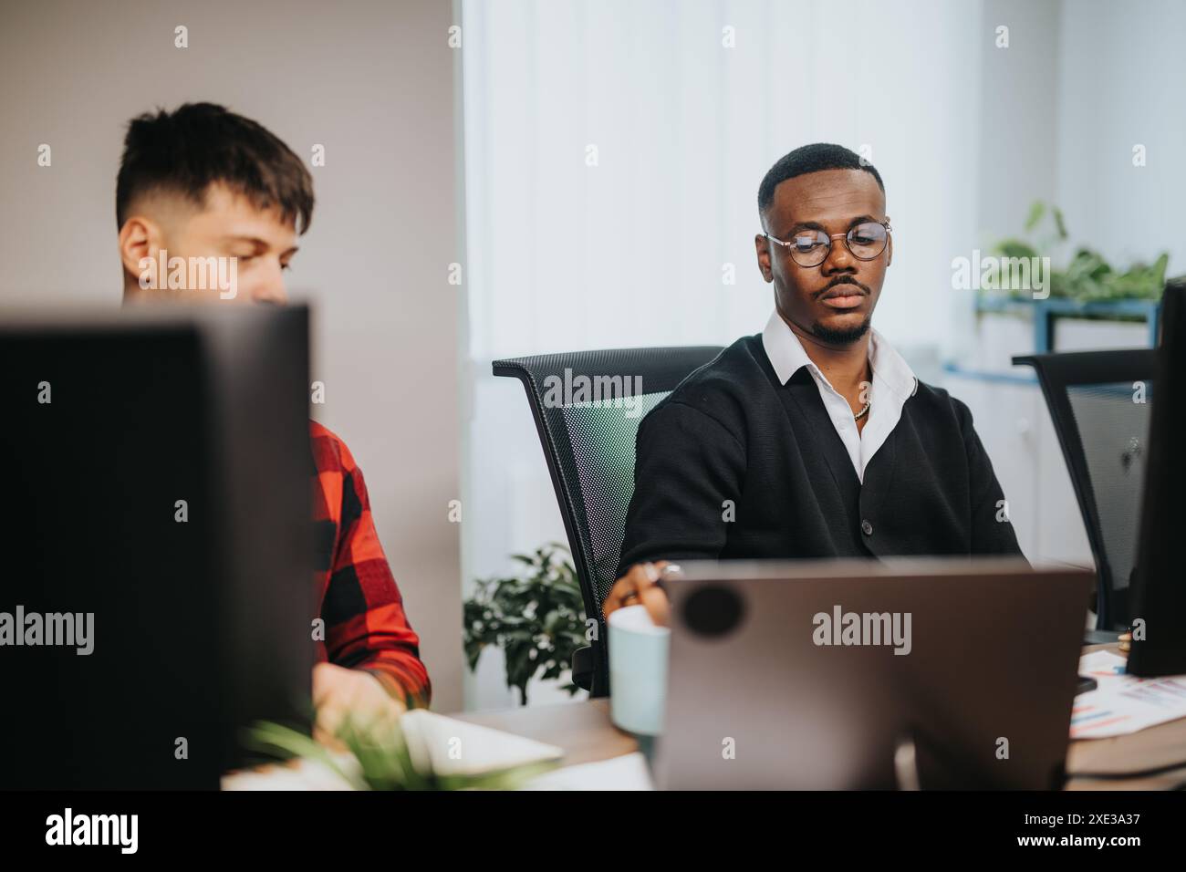 Diverse business team working at office desks, analyzing documents and using computers Stock Photo