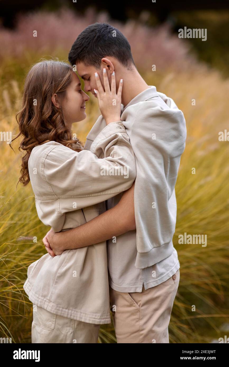 Happy couple on autumn walk outdoors. Two lovers in autumn park. Love and tender touch. Gentle hugs. Young man and woman in clas Stock Photo