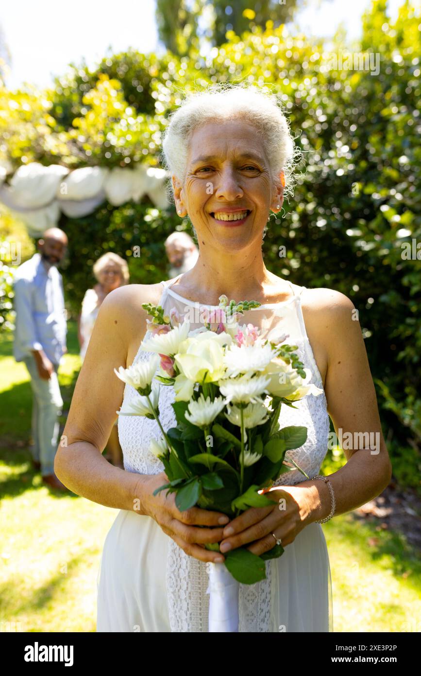 Smiling senior woman holding bouquet of flowers at outdoor wedding