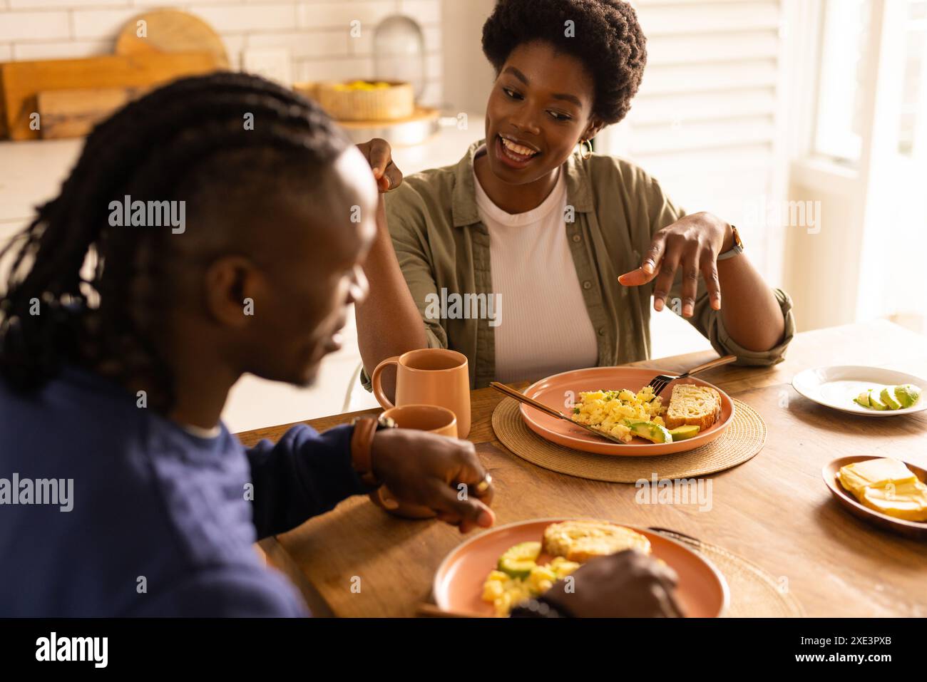 Couple enjoying breakfast together at home, smiling and having conversation Stock Photo