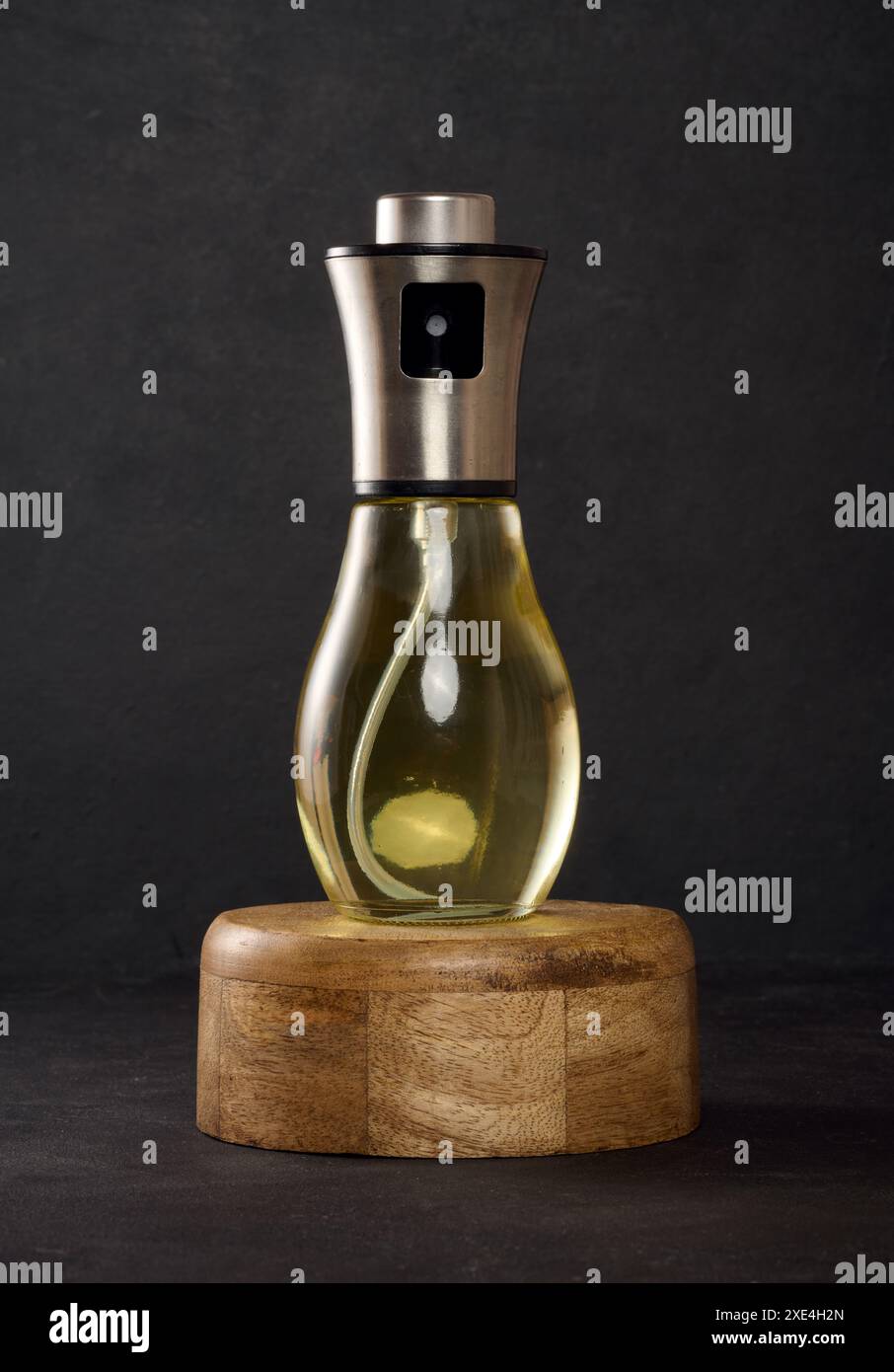 Glass transparent spray bottle filled with sunflower oil on a black table Stock Photo