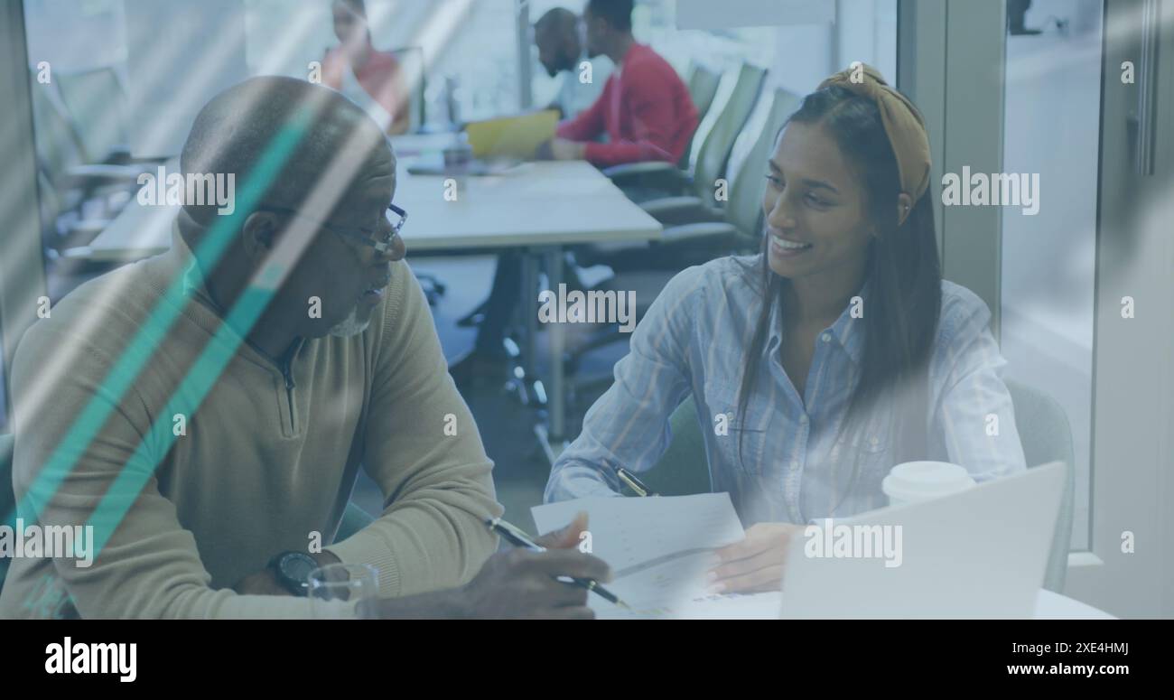 Image of multiple graphs and globe over multiracial colleagues analyzing documents on desk Stock Photo