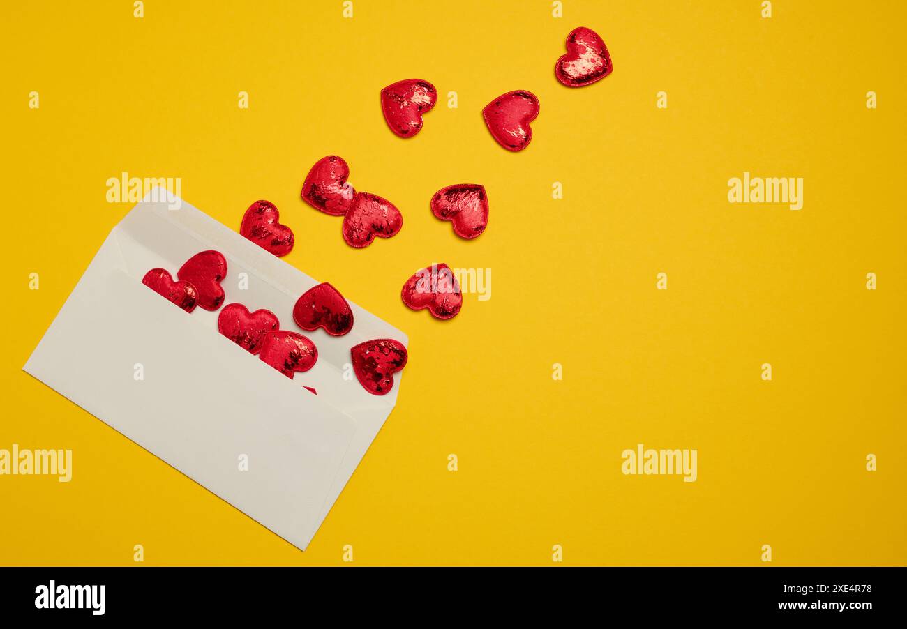 Rectangular white paper envelope and red hearts on a yellow background Stock Photo