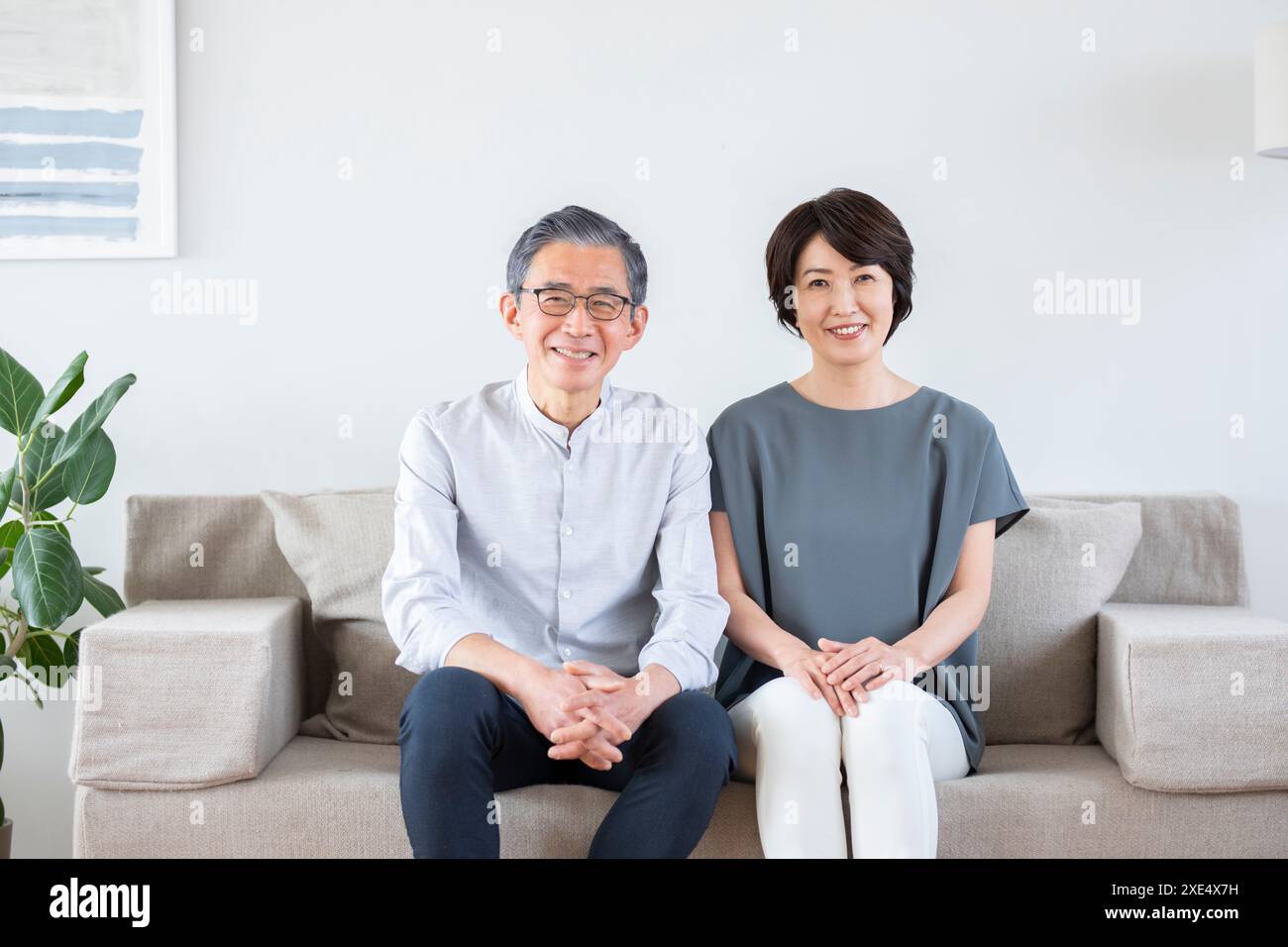 Senior couple sitting on a sofa and smiling Stock Photo