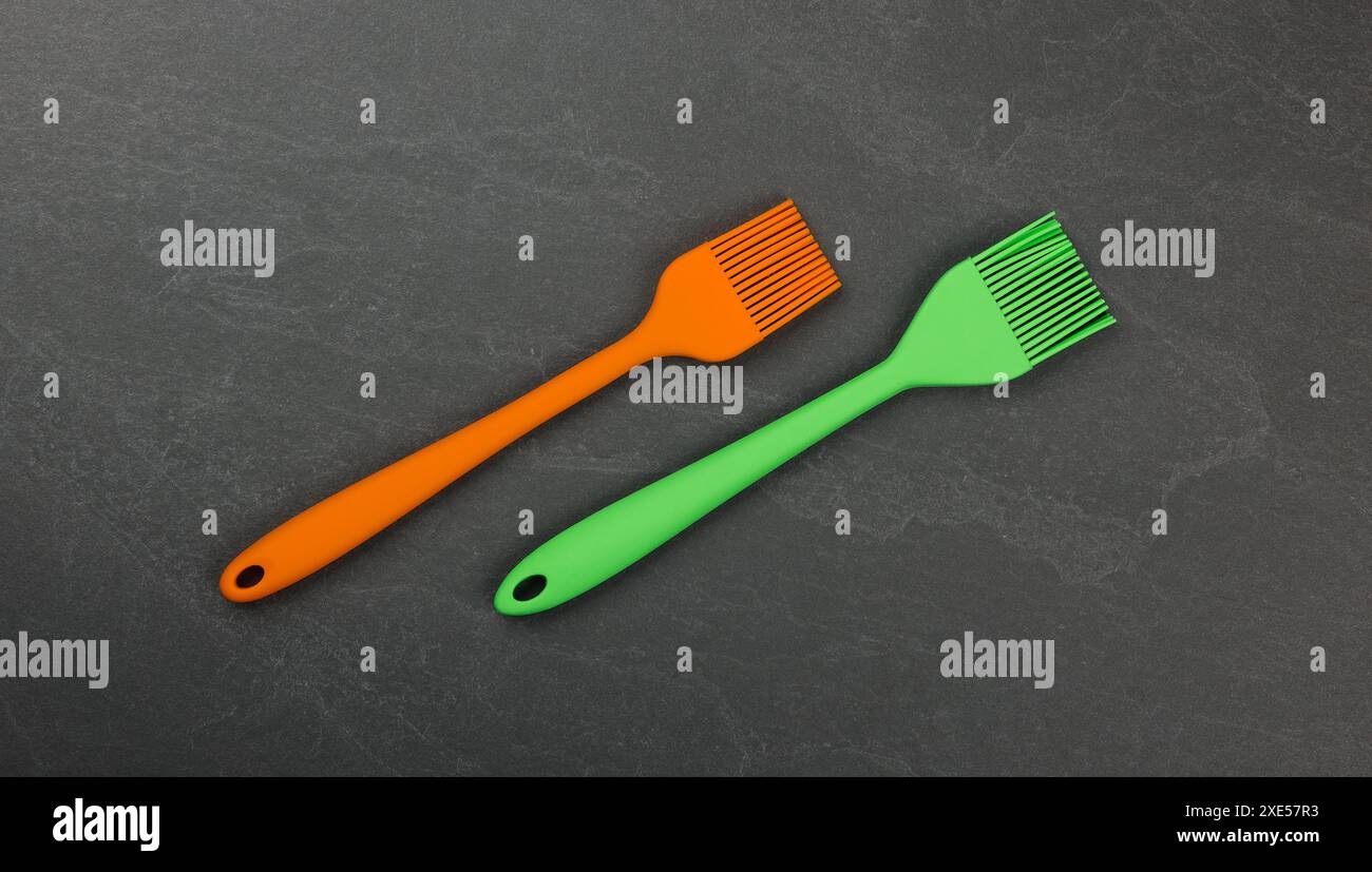 Two silicone culinary brushes on black slate board Stock Photo