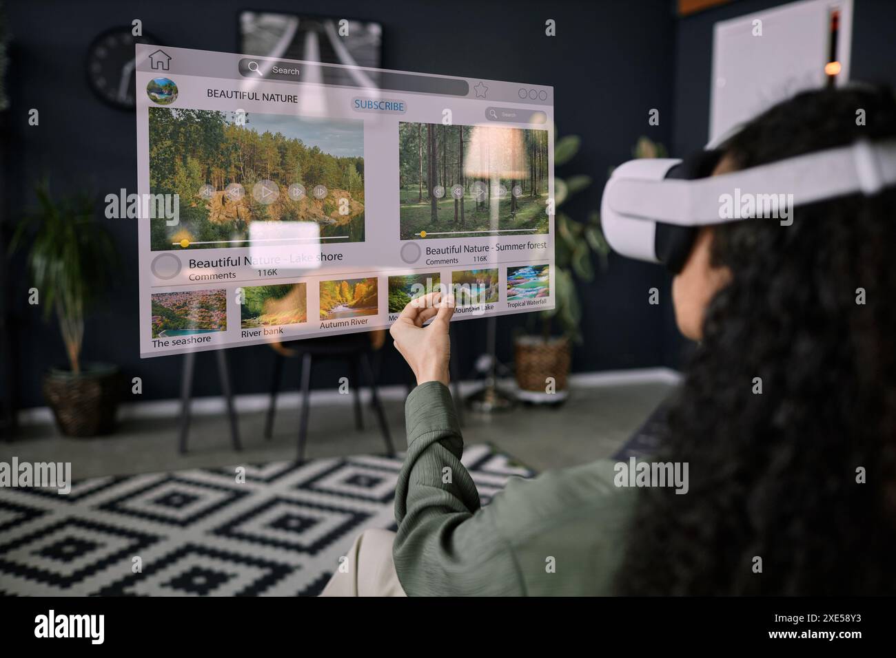 Over-the-shoulder shot of unrecognizable woman wearing VR headset sitting in living room surfing Internet Stock Photo