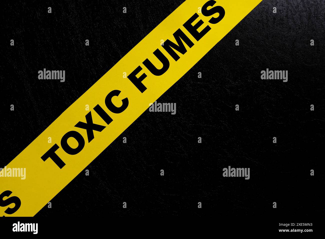 Toxic gas or fumes caution danger and warning concept. Yellow barricade tape with word in dark black background. Stock Photo