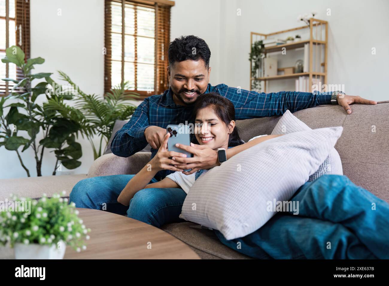 Happy Indian Couple Relaxing on Couch and Using Smartphone in Modern ...