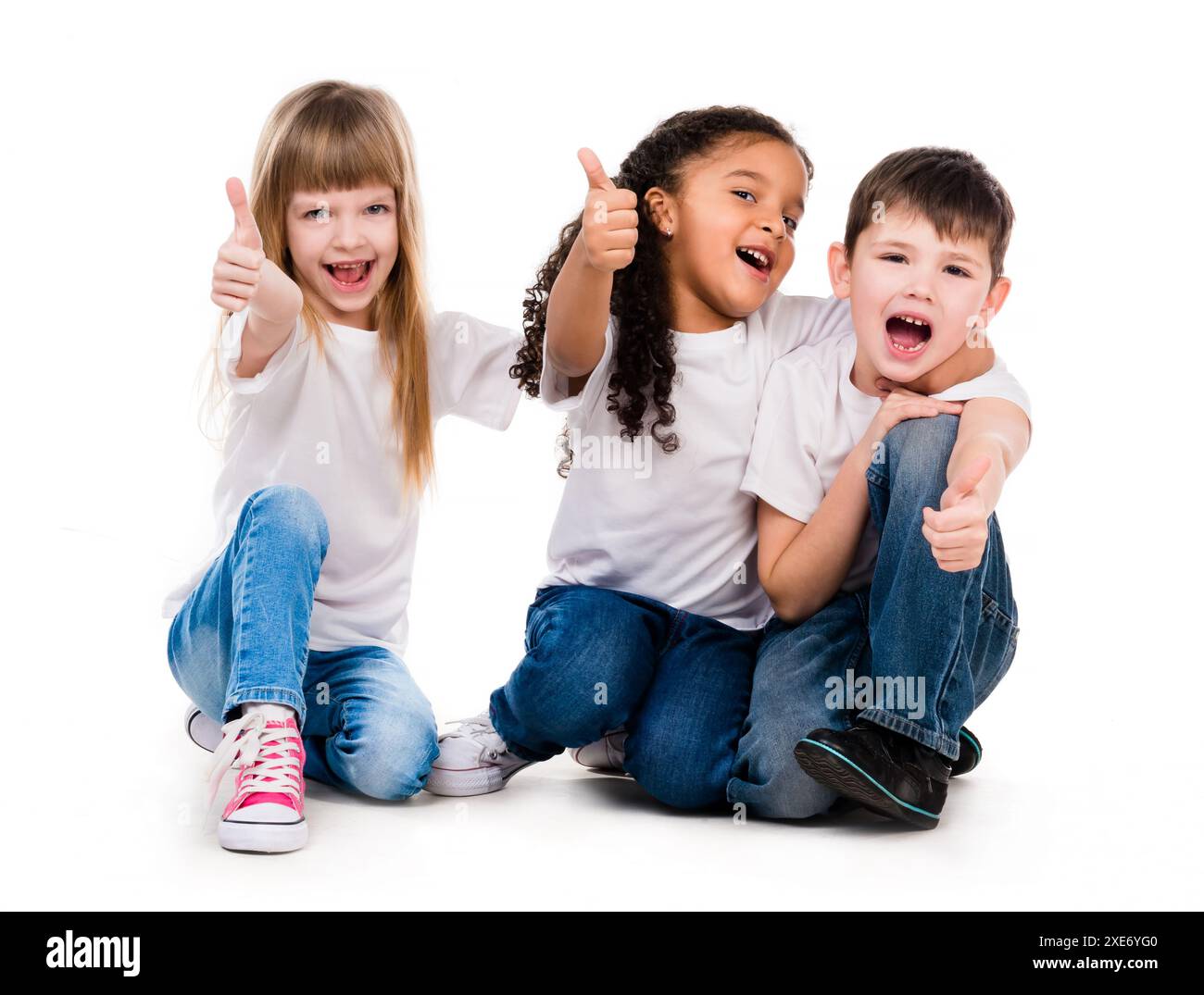 three funny children sitting on the floor with thumbs up isolated on ...