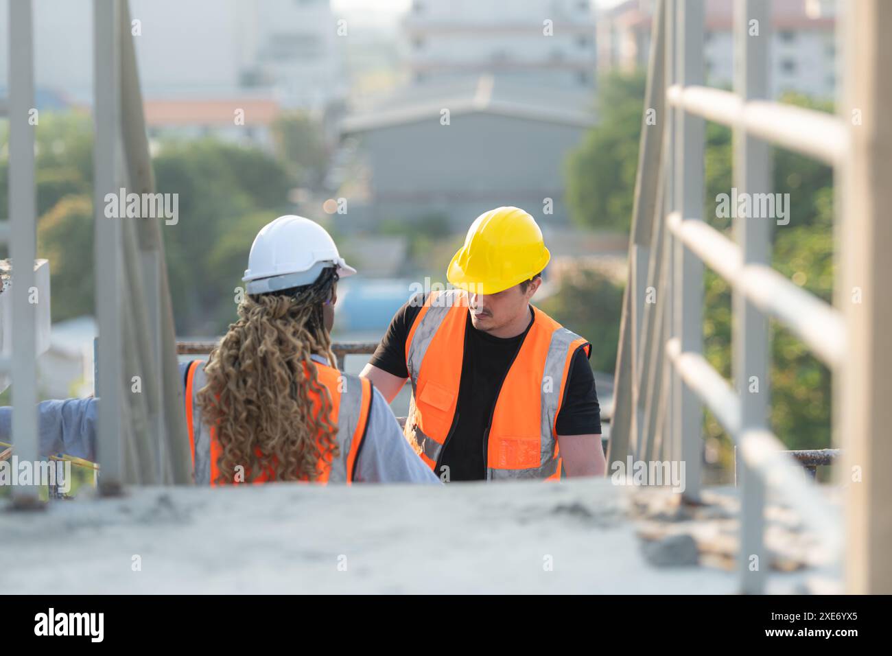 Male and female engineers working on construction site, They are inspecting the cement plaster work on the walls and balconies o Stock Photo