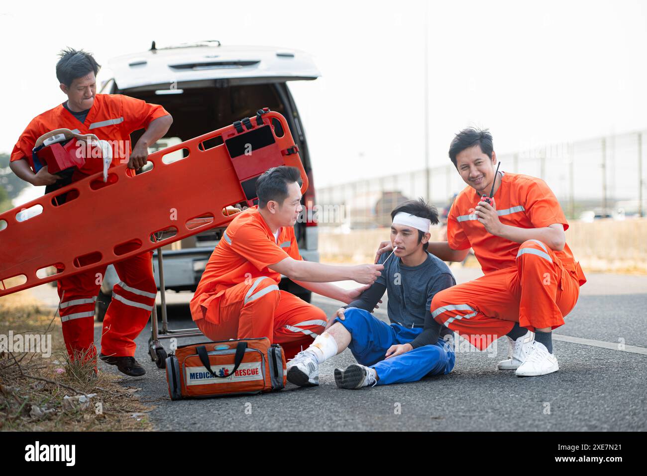 The paramedic  is assisting an injured man in an emergency situation on the road. Stock Photo