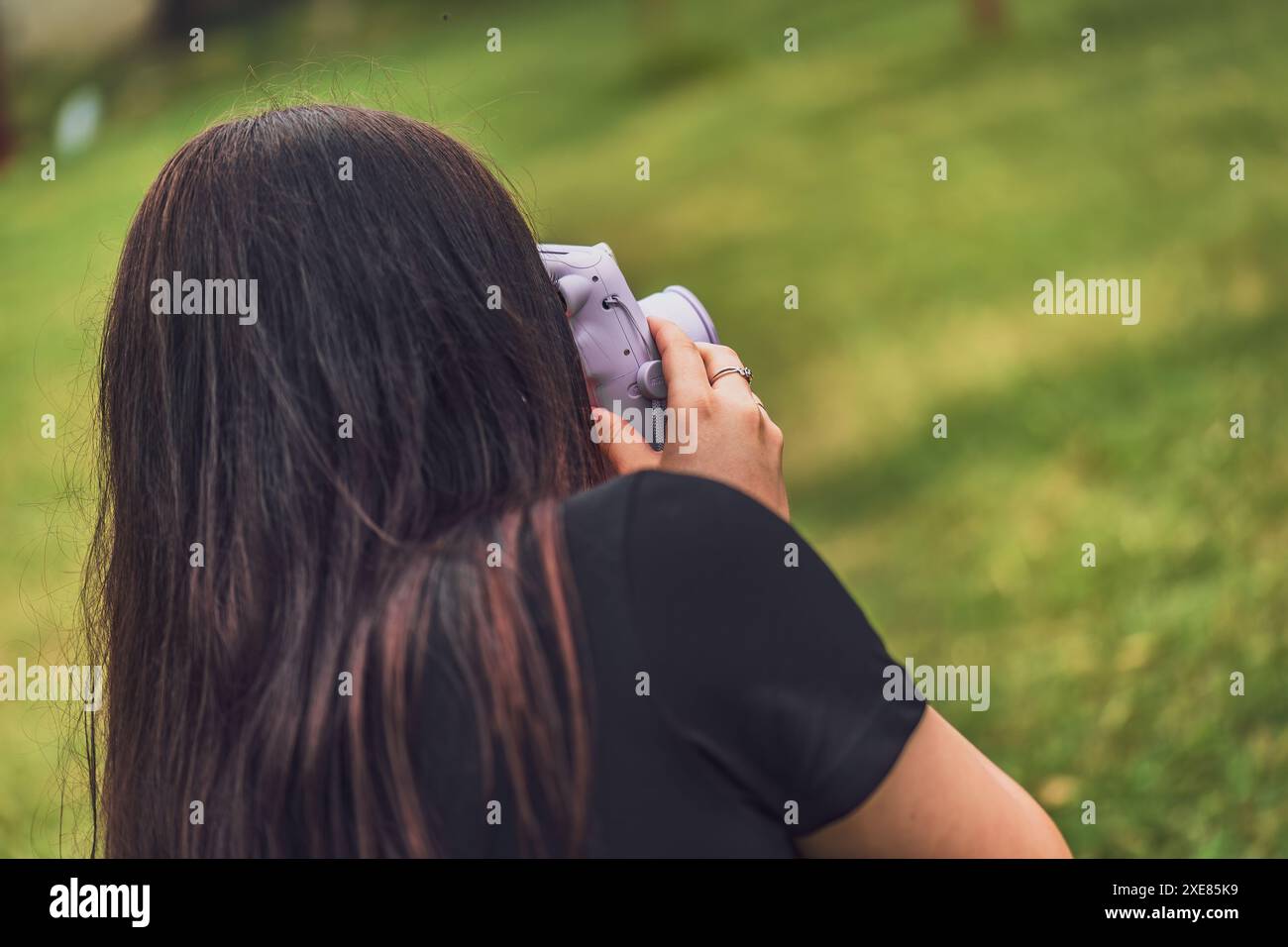 Instant Camera Back View Back view of a woman using an instant camera to take a photo in a ...