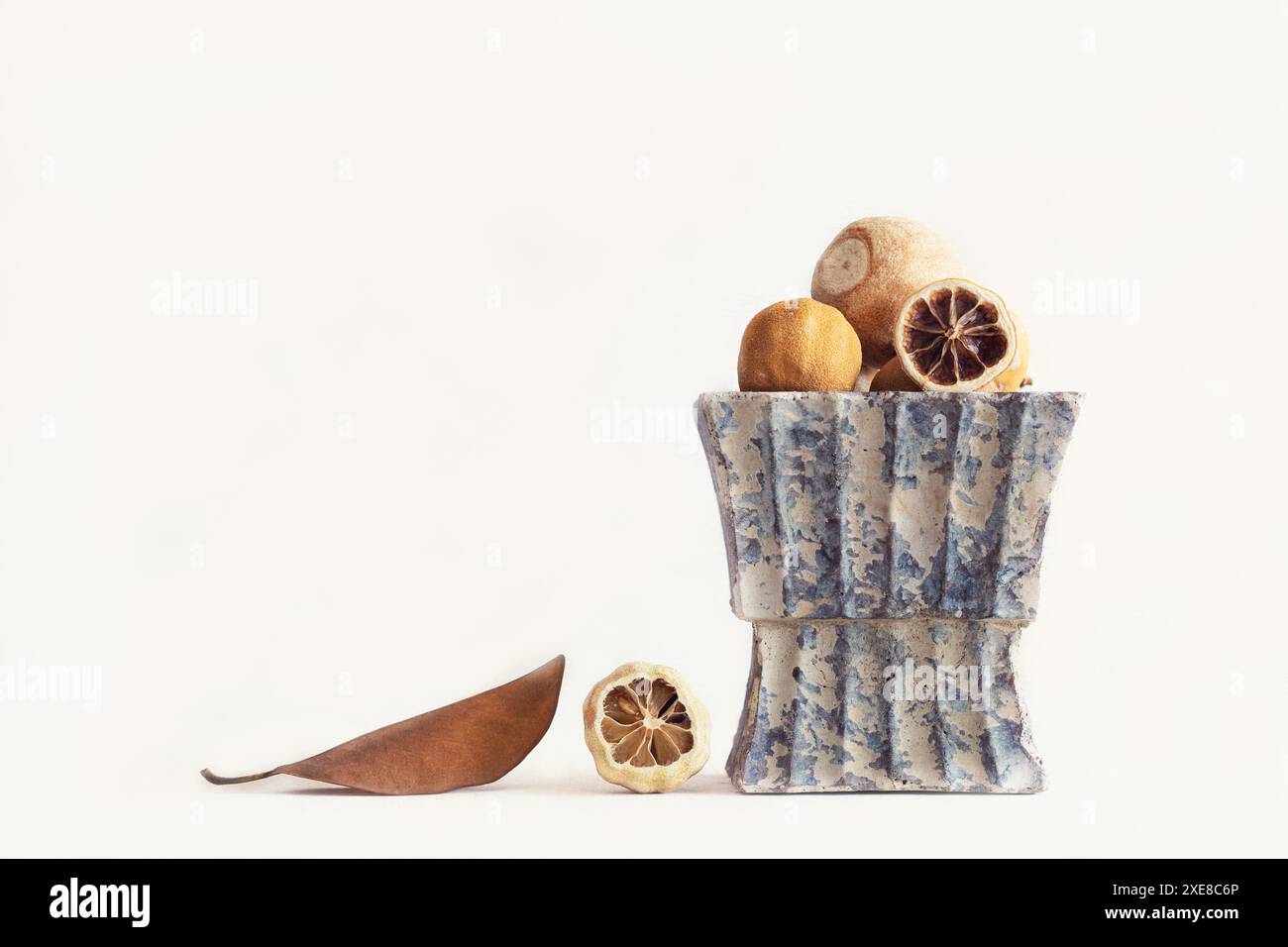 Creative still life of rustic vase with dried lemons and bay leaf ...