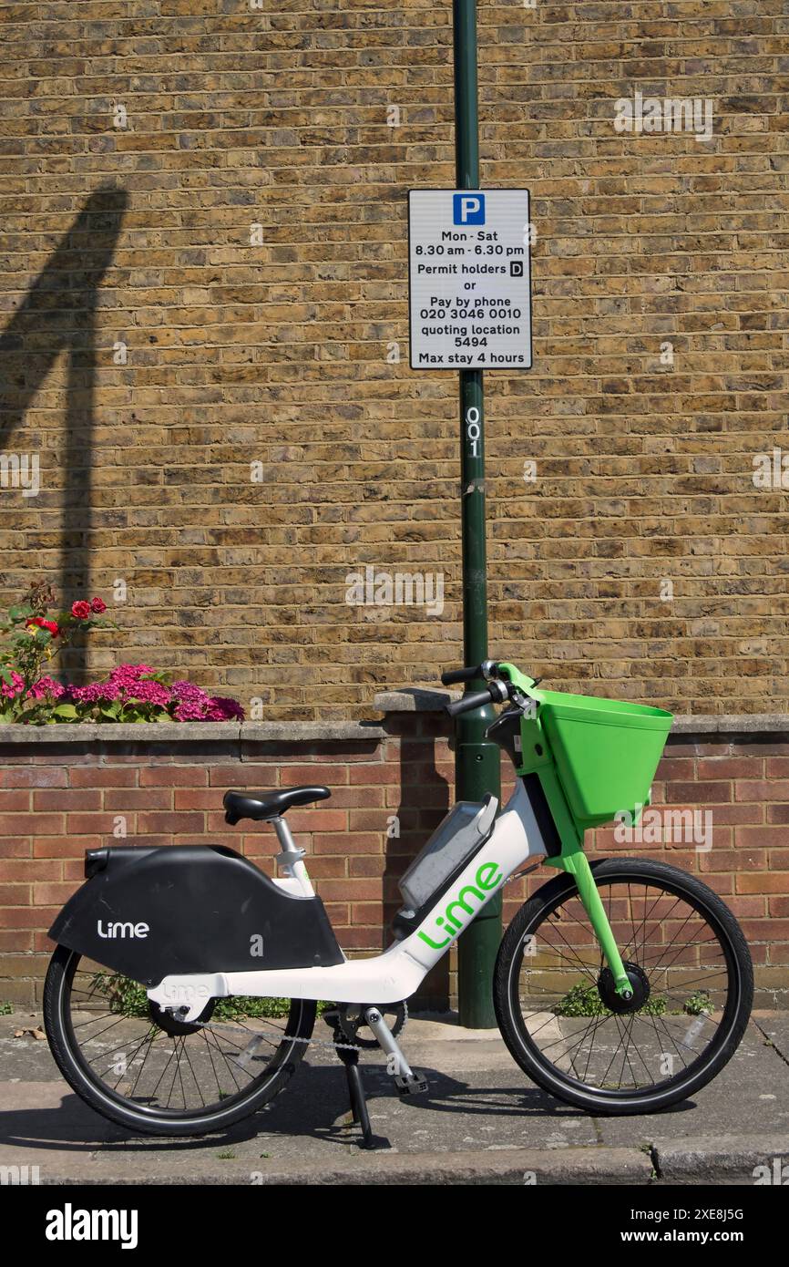 lime electric hire bike parked on a footway below a sign indicating vehicle parking restrictions