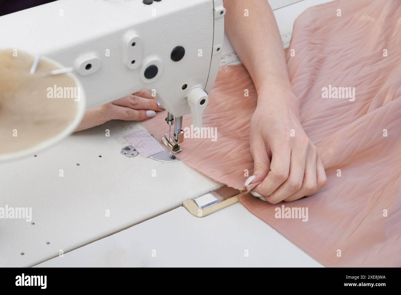 Dressmaker using sewing machine in tailor studio, modern atelier shop Stock Photo
