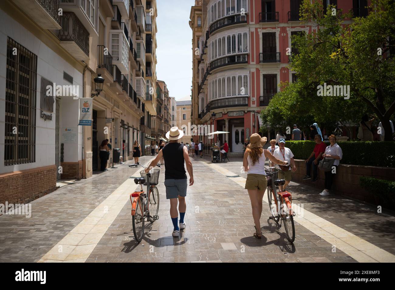 June 26, 2024, Malaga, Spain: A group of tourists are seen walking along a street with their bicycles in a downtown city, amid a context of increasing rejection of mass tourism. Malaga has experienced significant growth in mass tourism and an increase in the number of tourist apartments in the city centre and neighborhoods. These factors have resulted in rising rental and housing prices. Local neighbourhood associations and organisations are calling for measures to be introduced to limit rental prices and the impact of mass tourism. (Credit Image: © Jesus Merida/SOPA Images via ZUMA Press Wire Stock Photo