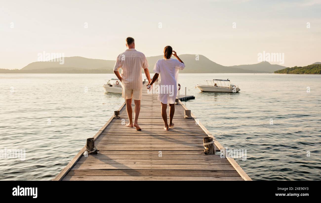 A man and a woman are standing on a dock holding hands Stock Photo