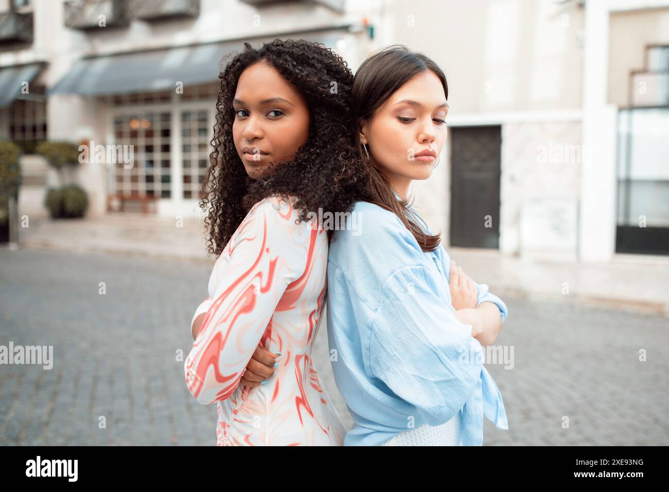 Two Women Standing Back To Back In Urban Setting Stock Photo - Alamy