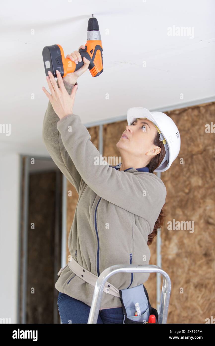 female builder using corless drill Stock Photo