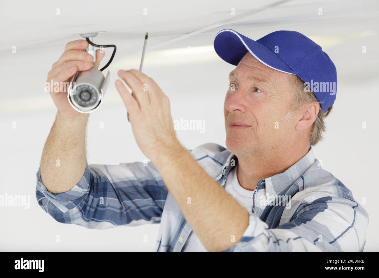 mature contractor installing cctv camera on ceiling Stock Photo