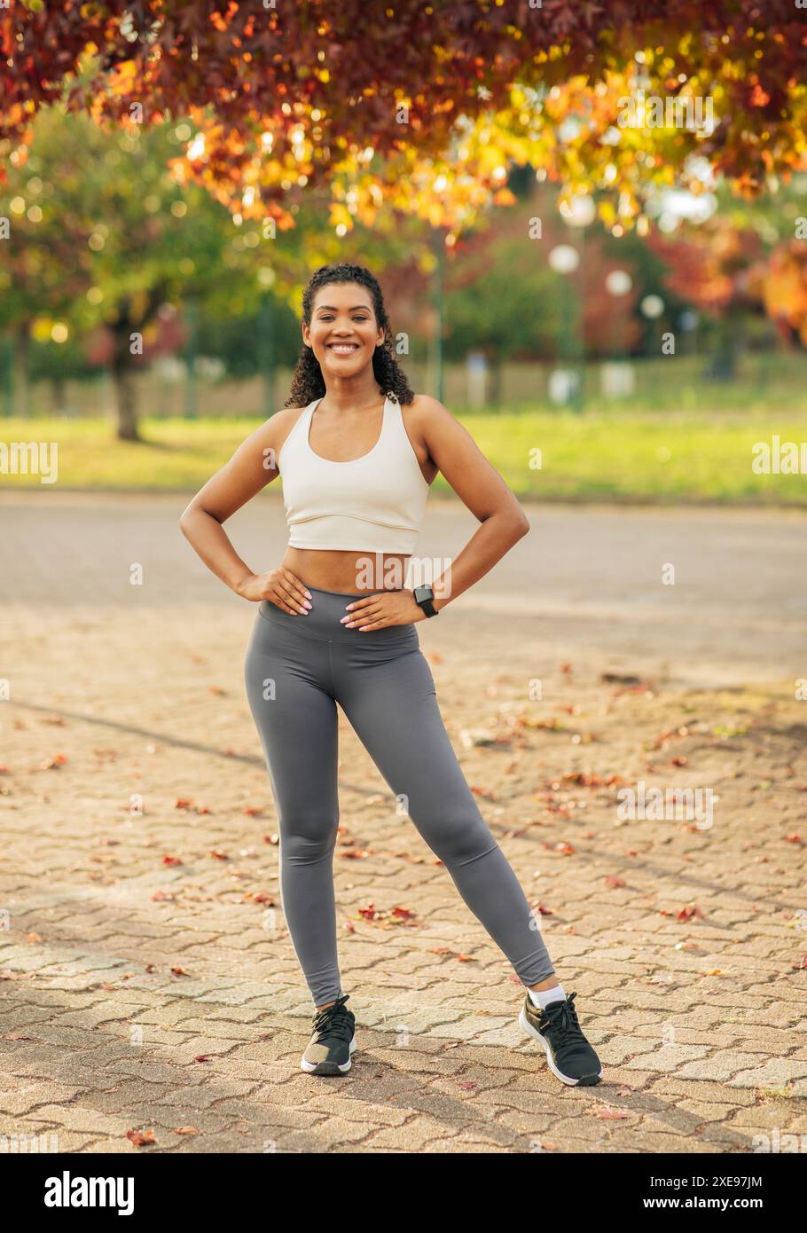 Woman Posing in Athletic Wear Under Autumn Tree Stock Photo