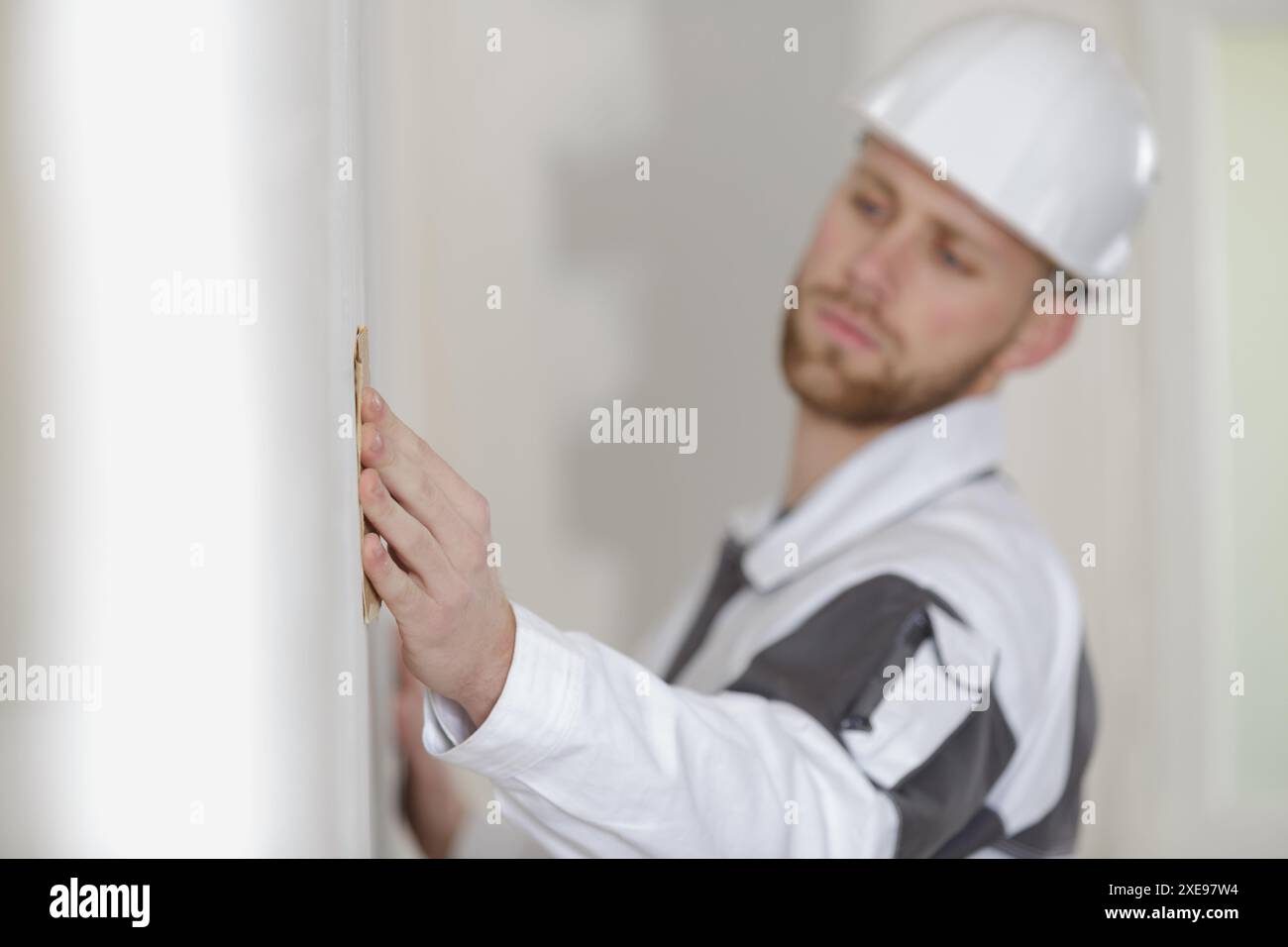 builder using sandpaper on interior wall Stock Photo