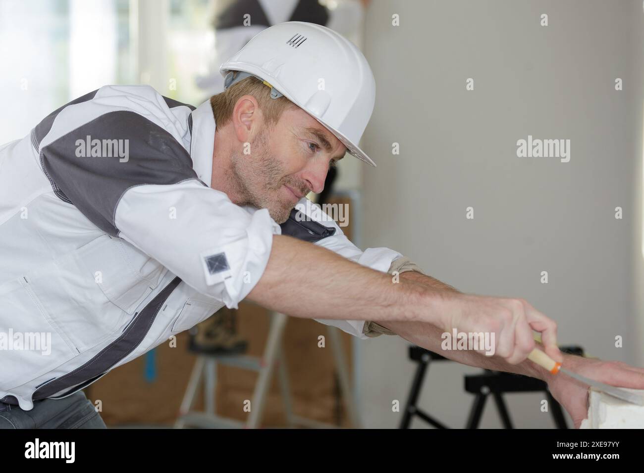 happy builder in hardhat plastering a wall Stock Photo