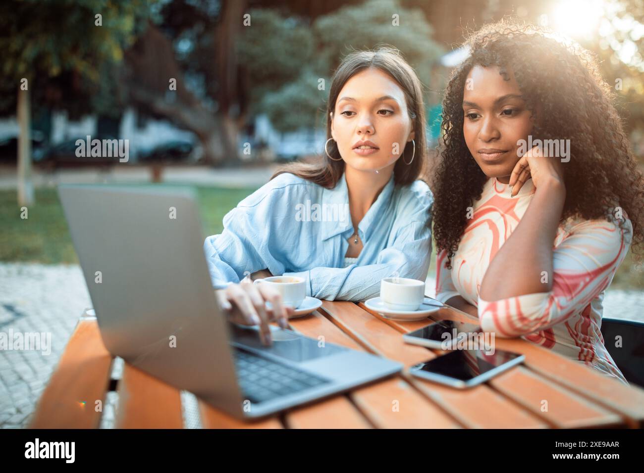 Two Women Working on Laptop at Outdoor Cafe Stock Photo