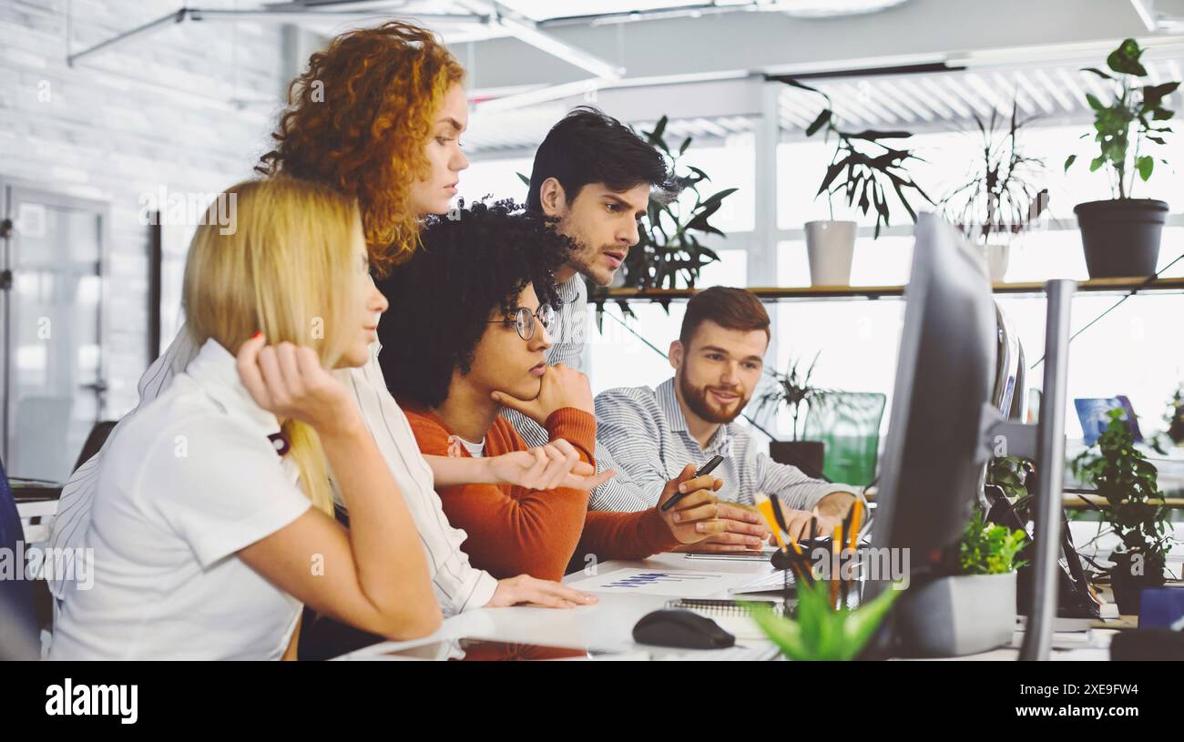 Young team analyzing new information, looking at computer Stock Photo