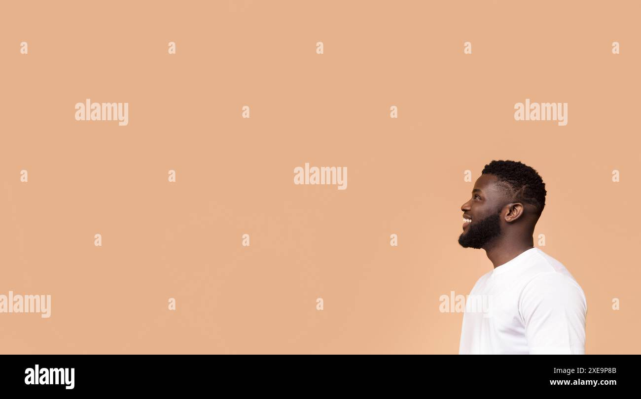 Smiling Black Man Looking Off Camera Against Peach Background Stock Photo