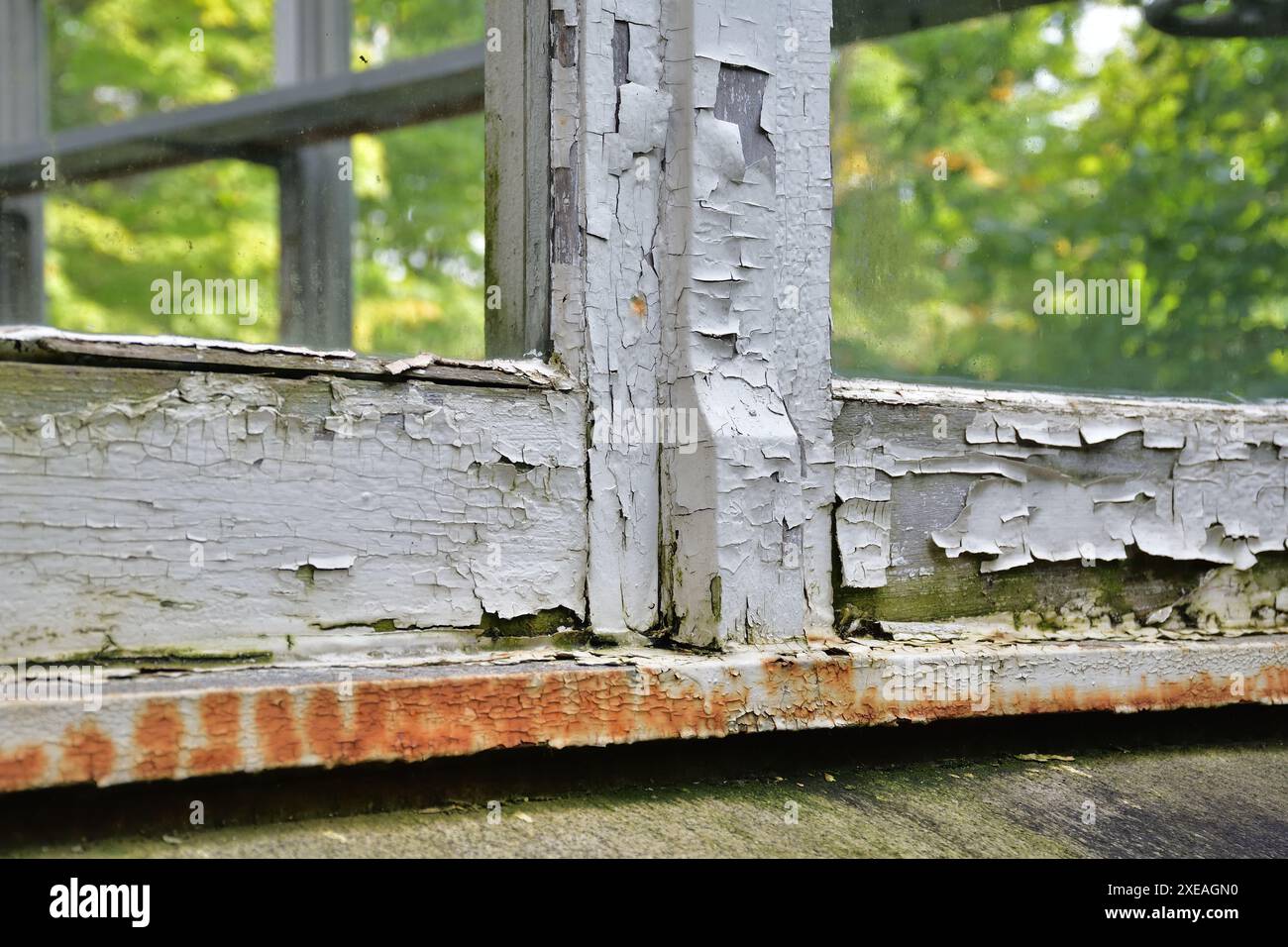 Wooden window frame damaged paint. Old window frame needing replacement. Paint job required. Old paint flaking. House maintenance needed concept. Stock Photo