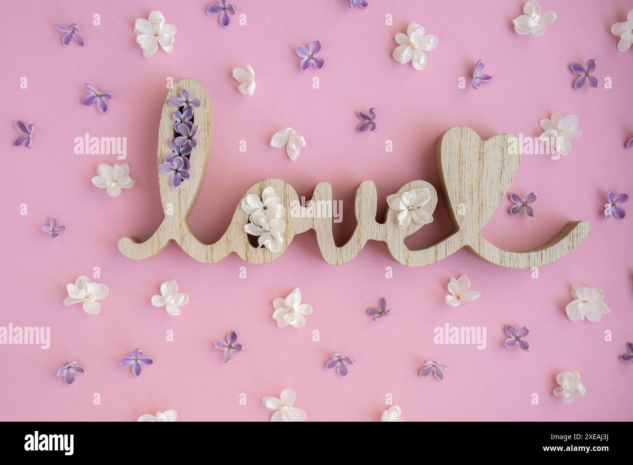 Wooden word LOVE and lilac flowers on pink purple background. St. Valentine Day, love or wedding day concept. Romantic backgroun Stock Photo