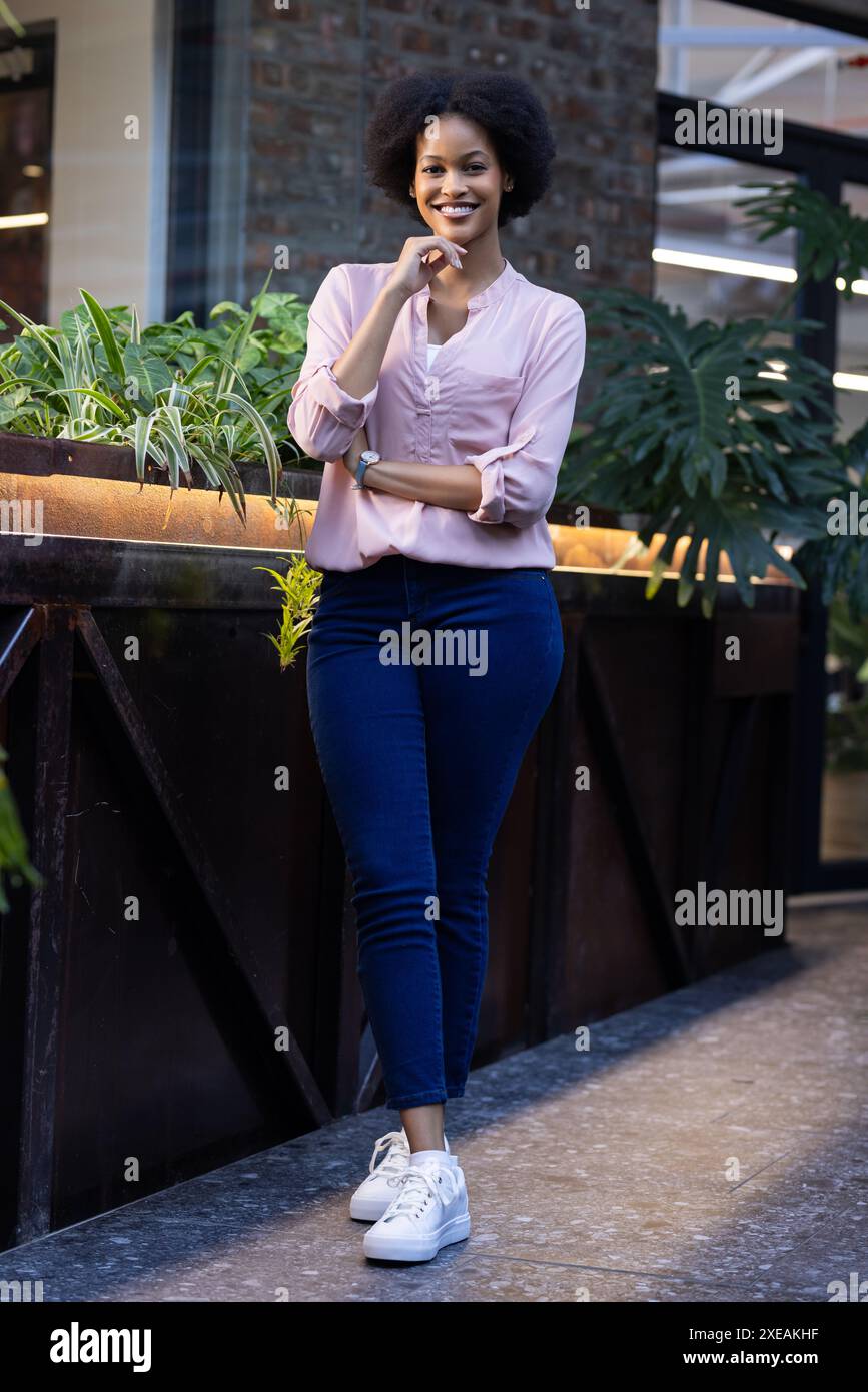 Smiling woman in casual business attire standing confidently in modern office Stock Photo
