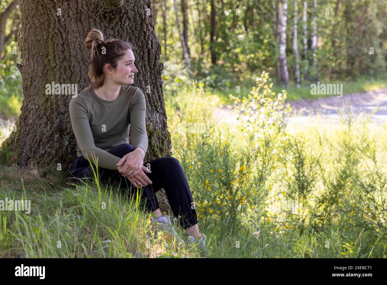 Joy in Nature's Lap: Smiling Woman Seated Under Tree Stock Photo - Alamy