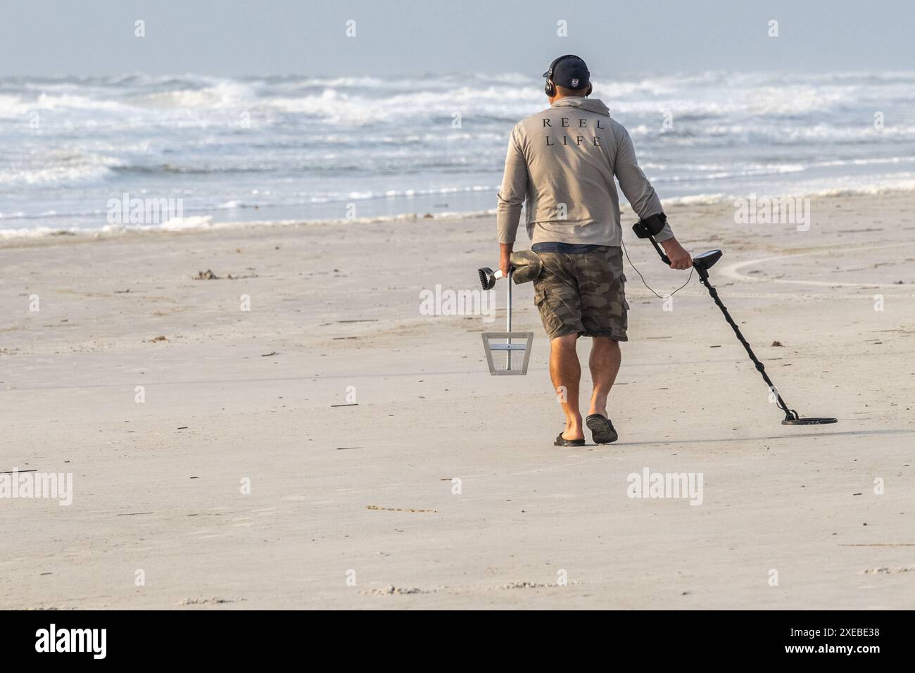 Florida beachcomber with handheld metal detector scanning the beach at Jacksonville Beach in Northeast Florida. (USA) Stock Photo